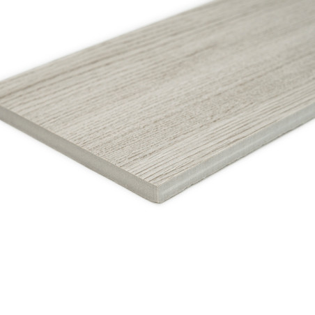 Un carreau rectangulaire gris clair avec un motif de grain de bois repose sur une surface blanche unie, mettant en valeur ses bo