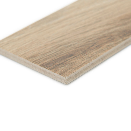 A rectangular, wood-patterned ceramic tile lies flat, displaying a natural, light brown grain texture. The surrounding area is a