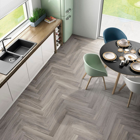 Des carreaux à chevrons en bois recouvrent le sol d'une cuisine moderne, entouré d'un meuble blanc, d'un évier et d'une table à 