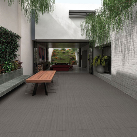 Uma mesa retangular de madeira, cercada por cadeiras transparentes, fica em um pátio moderno com vegetação pendurada acima e par