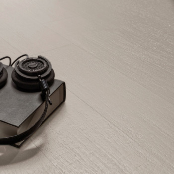 Los auriculares descansan sobre un libro negro cerrado, colocado sobre un piso o Azulejo texturizada de color claro, creando un 