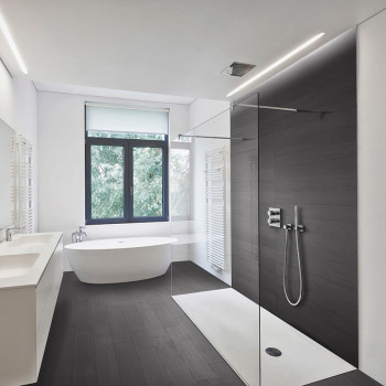 A modern bathroom features a sleek freestanding bathtub and wall-mounted shower in a spacious room with large window and dark fl