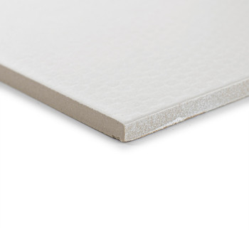 Eine weiße Fliese mit einer dezent strukturierten Oberfläche liegt auf einer ebenen Fläche und zeigt ihre Dicke und glatte Kante