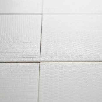 Les carreaux texturés blancs affichent des motifs subtils et variés dans une formation de grille, créant un design de surface mi