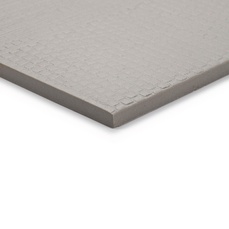 Um ladrilho cerâmico quadrado cinza, com um padrão de textura sutil, repousa sobre um fundo branco liso, mostrando sua borda lis