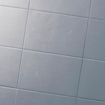 Ladrilhos cerâmicos quadrados com padrões sutis e texturizados dispostos em grade, refletindo a luz suavemente, criando uma supe