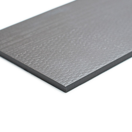 Un azulejo rectangular de color gris oscuro con una superficie ligeramente texturizada yace plano sobre un fondo blanco, mostran