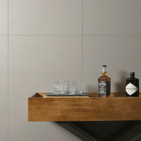 Two bottles, one `Jack Daniels` and one `Hendricks Gin,` rest on a wooden shelf with a crystal glass set. The background feature