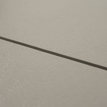 Un carreau de céramique lisse et beige repose à plat, adjacent à un autre sur une étroite ligne de coulis, formant une surface d