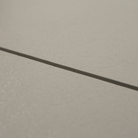 Un carreau de céramique lisse et beige repose à plat, adjacent à un autre sur une étroite ligne de coulis, formant une surface d