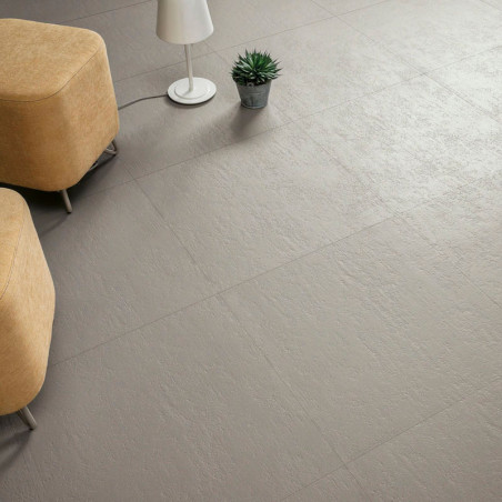 Gray tiles form a textured floor, supporting two beige ottomans, a white floor lamp, and a small potted plant nearby.