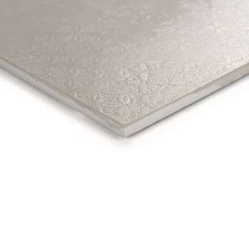 Un carreau beige présente une surface subtilement texturée avec des motifs circulaires, vus en gros plan, placés sur un fond bla