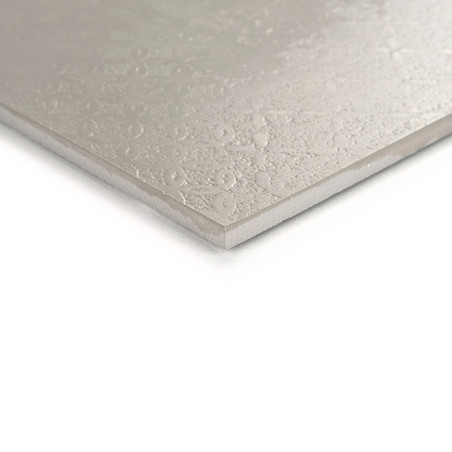 Um ladrilho bege exibe uma superfície de textura sutil com padrões circulares, vistos em close, colocados sobre um fundo branco.