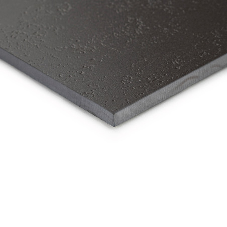 A smooth, black tile with a textured surface rests on a flat surface, emphasizing its thin edges and matte finish.