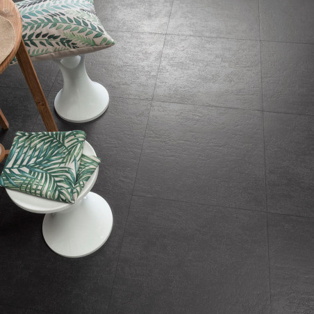 Les carreaux de sol gris foncé texturés présentent un motif en grille. Des tabourets rembourrés avec des oreillers à motifs de f