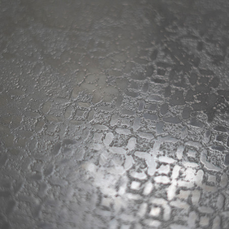 Une surface en verre texturé et dépoli présente un motif géométrique complexe et répétitif, réfléchissant doucement la lumière d