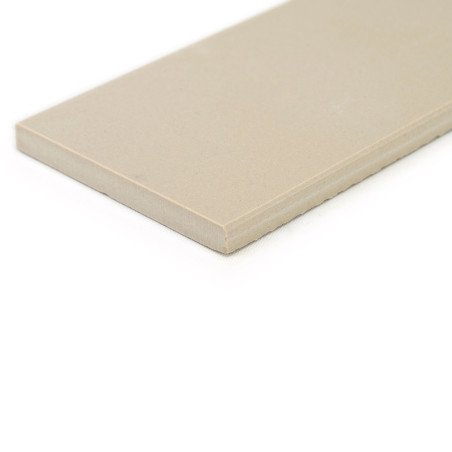 Un azulejo rectangular de color beige se apoya sobre un fondo blanco, mostrando su superficie lisa y sus bordes rectos y preciso