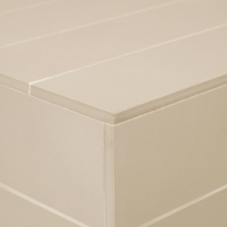 Eine beige rechteckige Fliese mit glatter Oberfläche, die Teil eines strukturierten, geschichteten Musters in einer minimalistis