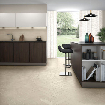 La cuisine présente un sol en carrelage clair à chevrons, des armoires en bois sombre, un comptoir avec des étagères ouvertes, d