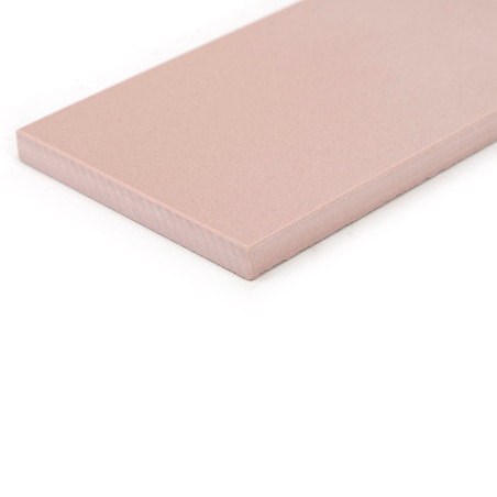 Un azulejo cerámico rectangular de color rosa descansa sobre un fondo blanco, presenta una superficie lisa y bordes ligeramente 