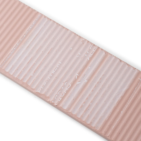 Un azulejo cerámico rectangular de color beige presenta una textura acanalada y un texto sangrado que dice `TILE LINES`, con un 