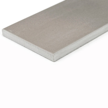 Un azulejo gris rectangular se apoya sobre un fondo blanco, mostrando su superficie lisa y su espesor uniforme.