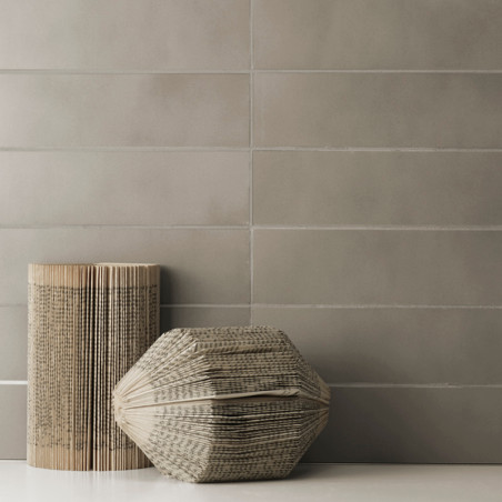 Rechteckige graue Fliesen bilden einen glatten, gleichmäßigen Wandhintergrund. Zwei skulpturale, buchartige Objekte mit sichtbar Rechteckige graue Fliesen bilden einen glatten, gleichmäßigen Wandhintergrund. Zwei skulpturale, buchartige Objekte mit sichtbar