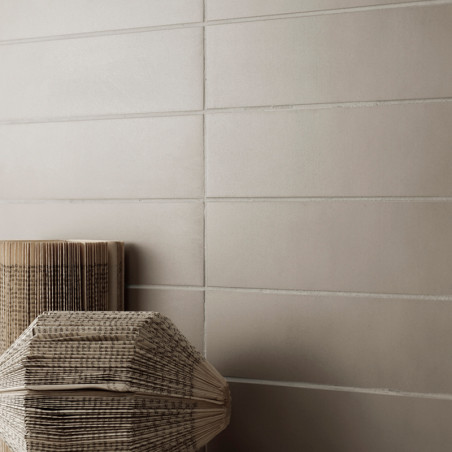 Los azulejos de color beige neutro forman una pared lisa dispuesta horizontalmente, con linternas de papel plegadas apoyadas con