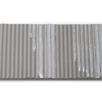 O ladrilho é uma faixa retangular com estrias verticais e apresenta o texto impresso: `MADE IN ITALY, CERAMICA.` Sua superfície 