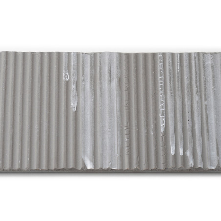 De tegel is een rechthoekige strook met verticale randen en bevat de tekst: `MADE IN ITALY, CERAMICA.` Het oppervlak vertoont dr