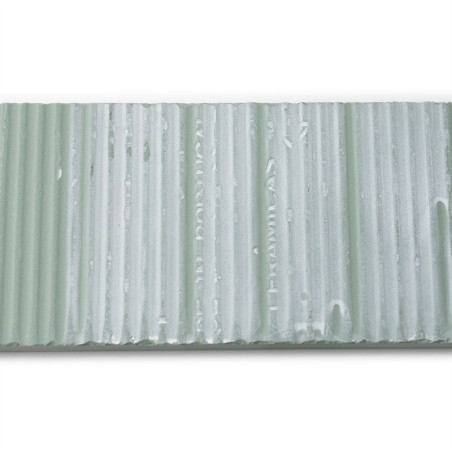 Un carreau texturé rectangulaire présente des rainures verticales et une teinte vert pâle avec un texte pâle : « CUMEL CA 45 HEL