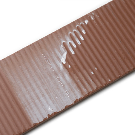 Un carreau de céramique marron rectangulaire et nervuré avec une strie blanche brillante en diagonale. Le texte en relief indiqu