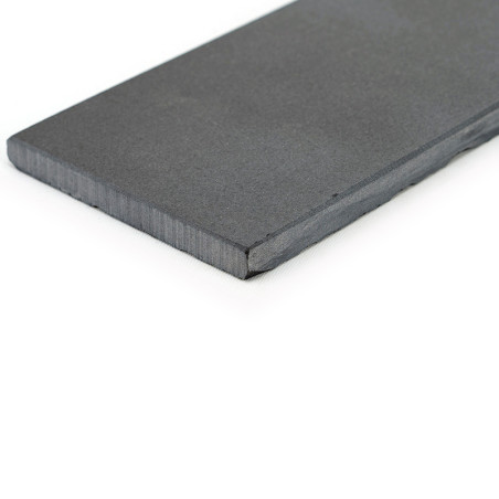Una losa de pizarra rectangular, plana, de color gris oscuro, descansa sobre una superficie blanca, mostrando una textura suave 