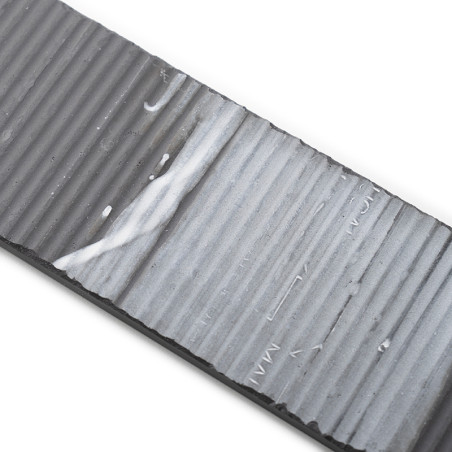 Un carreau rectangulaire nervuré présente un dégradé allant du gris foncé au gris clair avec des rainures texturées. Des stries 