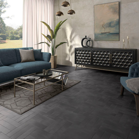 Un carrelage gris à chevrons recouvre le sol du salon, entouré d'un canapé bleu, d'une table basse en verre et d'œuvres d'art ab