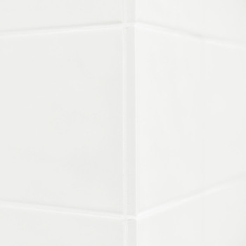 Ladrilhos cerâmicos brancos formam um canto limpo, refletindo a luz sutilmente. A superfície lisa sugere um ambiente de banheiro