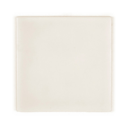 Um ladrilho cerâmico liso e quadrado repousa sobre um fundo branco, exibindo uma superfície branco-creme uniforme com variações 