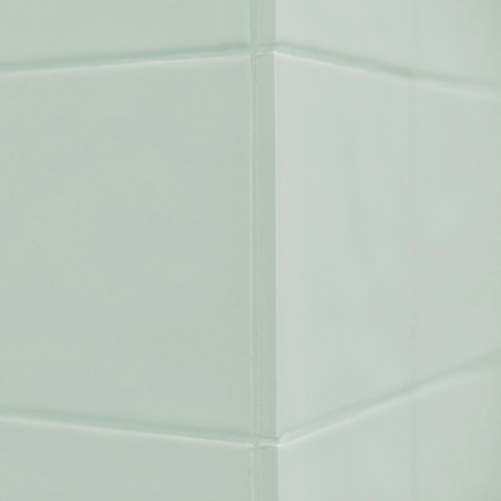 Een lichtgroene keramische tegel vormt een hoek met strakke, rechte voegen die in een rechte hoek samenkomen, waardoor een naadl Een lichtgroene keramische tegel vormt een hoek met strakke, rechte voegen die in een rechte hoek samenkomen, waardoor een naadl