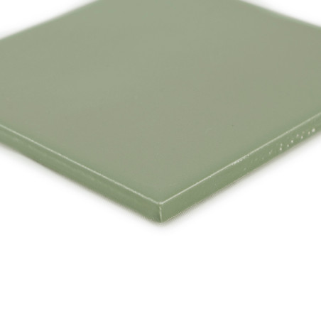Un carreau vert carré et lisse repose sur une surface blanche, affichant un éclat subtil avec des bords légèrement arrondis et a Un carreau vert carré et lisse repose sur une surface blanche, affichant un éclat subtil avec des bords légèrement arrondis et a