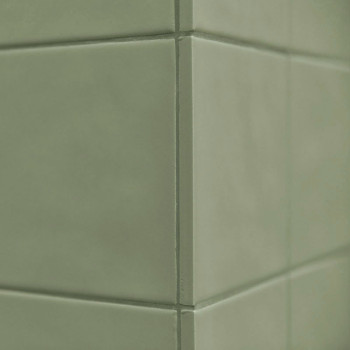 Les carreaux de céramique verte forment un coin, créant une surface propre et lisse dans un décor intérieur minimaliste.