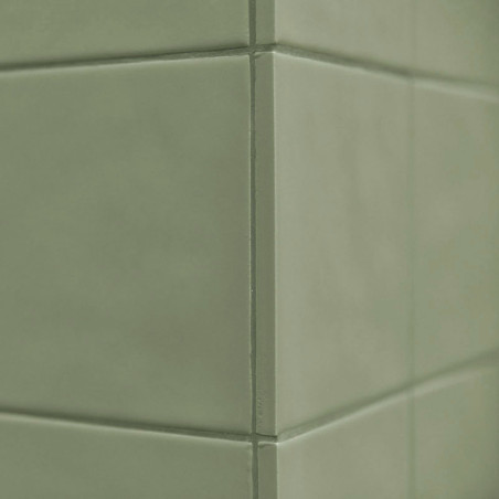 Grüne Keramikfliesen bilden eine Ecke und schaffen eine saubere, glatte Oberfläche in einer minimalistischen Inneneinrichtung.