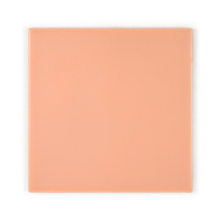 A smooth, peach-colored ceramic tile rests on a plain white background. The tile is square with a glossy finish and no text.
