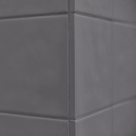 Los azulejos cerámicos grises forman una esquina afilada, alineada verticalmente con superficies lisas, en un ambiente interior 
