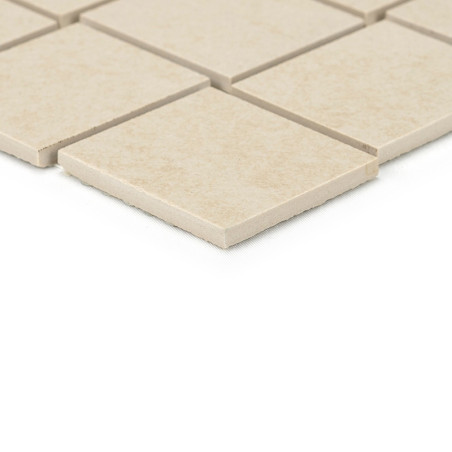 Carreaux de céramique carrés beiges alignés selon un motif de grille, présentant des bords nets. ils reposent sur une surface pl