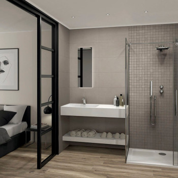 Een moderne badkamer is voorzien van een strakke douche, aan de muur gemonteerde wastafel met flessen en een grote spiegel, gren