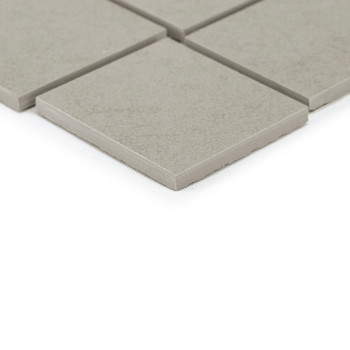 Gray square tiles rest on a smooth surface, with one tile slightly overlapping others, creating a simple, uniform grid layout.