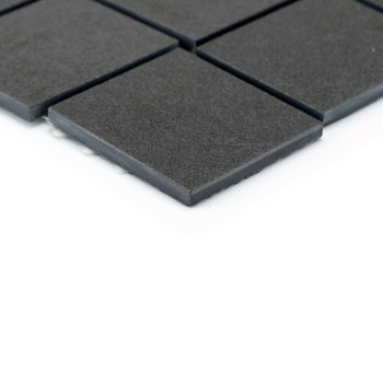 Square black tiles, arranged in a grid pattern, rest on a white background. The tiles appear slightly elevated, suggesting a sle