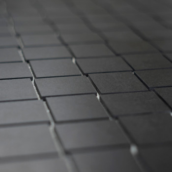 Les carreaux carrés sombres et mats sont disposés selon un motif en grille, créant une surface homogène et uniforme qui s'étend 