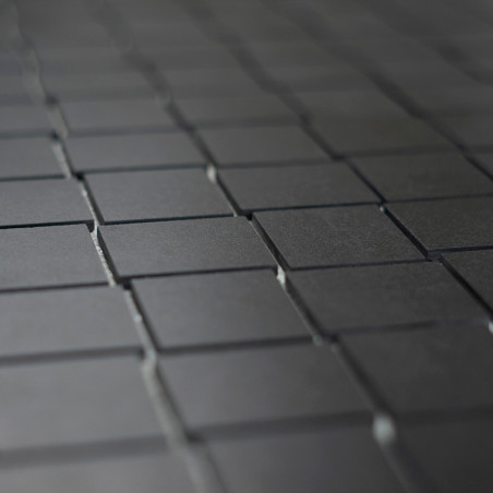 Les carreaux carrés sombres et mats sont disposés selon un motif en grille, créant une surface homogène et uniforme qui s'étend 