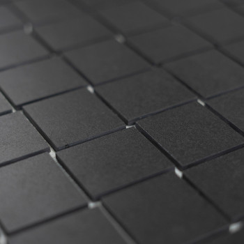 Les carreaux carrés sombres sont disposés selon un motif en grille, créant une surface uniforme et minimaliste qui suggère un re